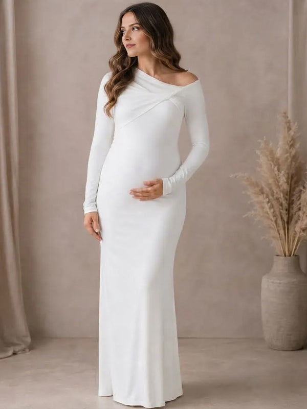 Side view of white jersey maternity maxi dress with asymmetric twisted neckline and long sleeves, designed for maternity photoshoot.