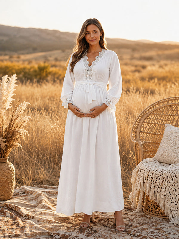 White boho maternity maxi dress with lace-trimmed V-neck, long sleeves and tie waist, designed for maternity photoshoot.