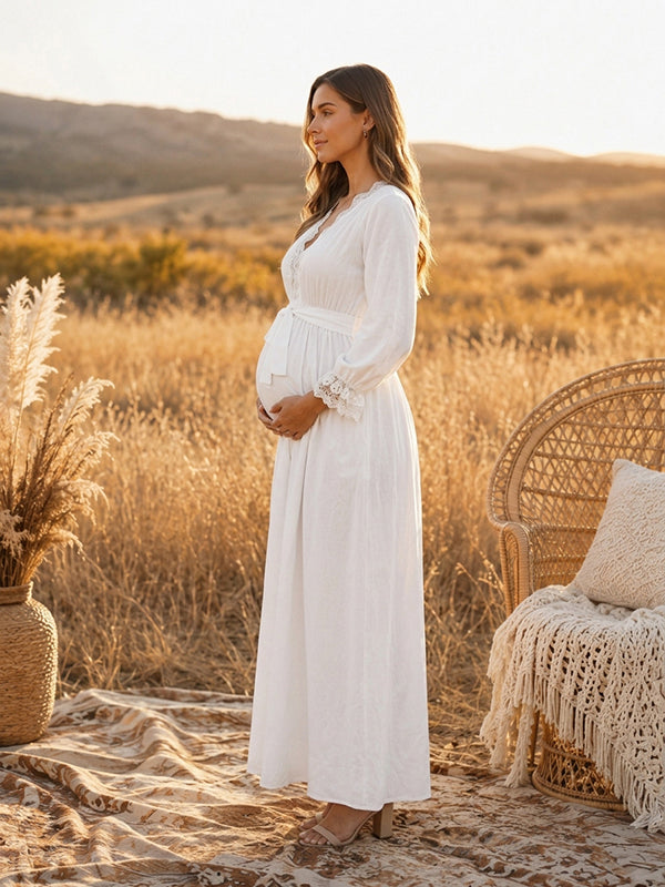 Side view of white boho maternity maxi dress with lace-trimmed V-neck, long sleeves and tie waist, designed for maternity photoshoot.