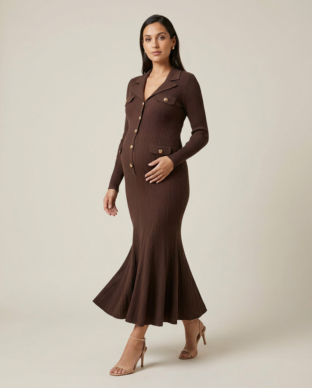 Brown ribbed knit maternity maxi dress with collar, gold buttons and fluted hem, shown on a pregnant model in studio.