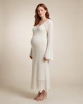 Ivory crochet knit maternity maxi dress with bell sleeves and scalloped hem, shown on a pregnant model in studio.