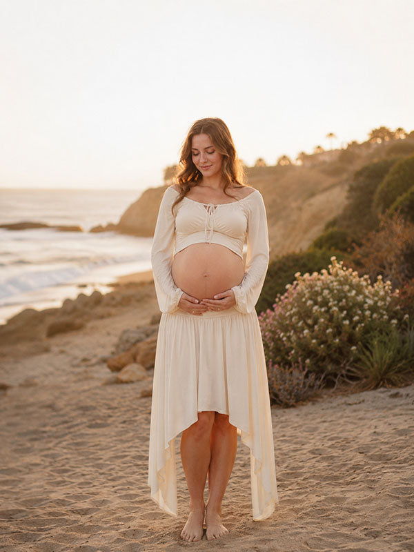 Ivory maternity two-piece set with bell sleeve crop top and high-low skirt, designed for beach photoshoot.