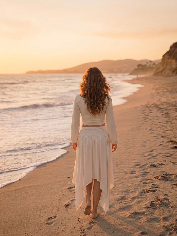 Back view of ivory maternity two-piece set with bell sleeve crop top and high-low skirt, designed for beach photoshoot.
