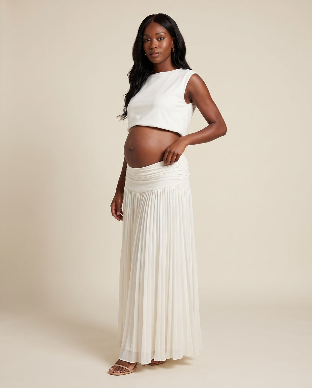 White maternity two-piece set with cropped top and pleated maxi skirt, designed for beach maternity photoshoots.