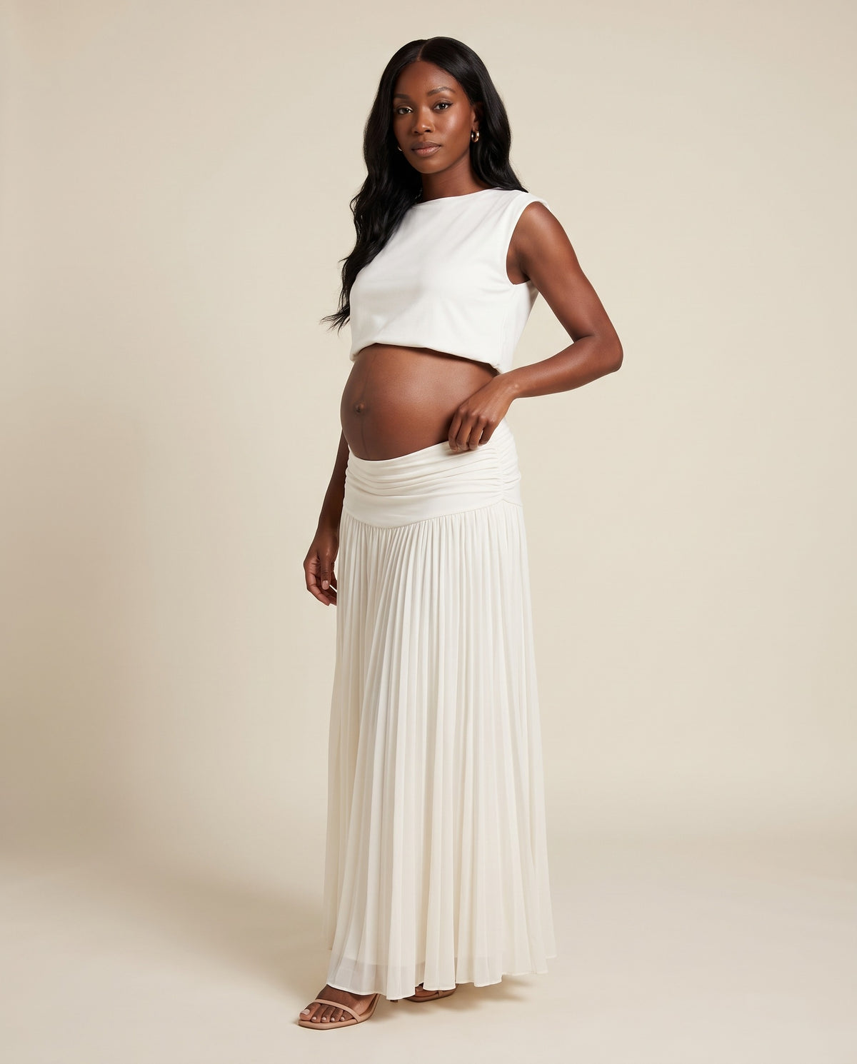 White maternity two-piece set with cropped top and pleated maxi skirt, designed for beach maternity photoshoots.