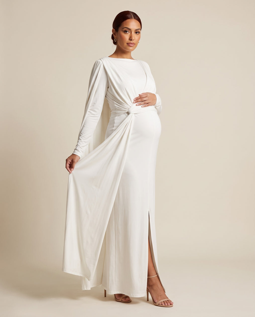 White jersey maternity maxi dress with draped cape overlay and waist knot sash, designed for maternity photoshoots.