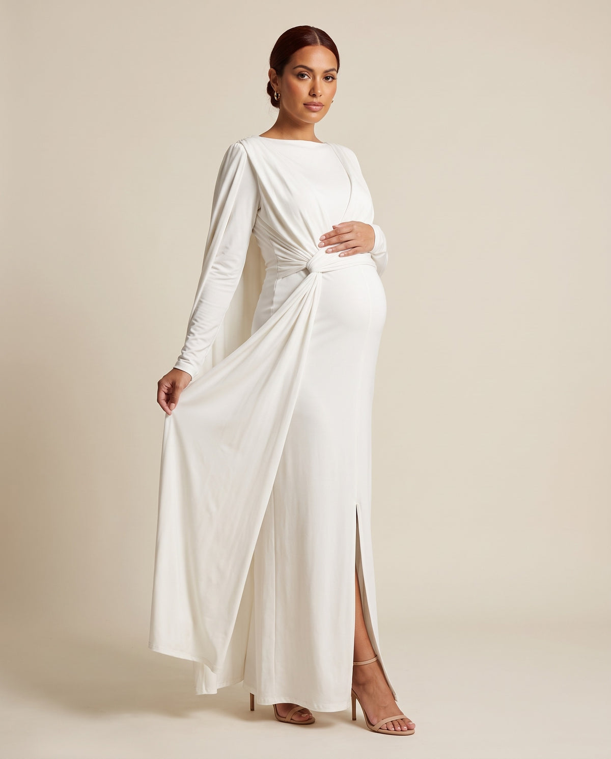 White jersey maternity maxi dress with draped cape overlay and waist knot sash, designed for maternity photoshoots.