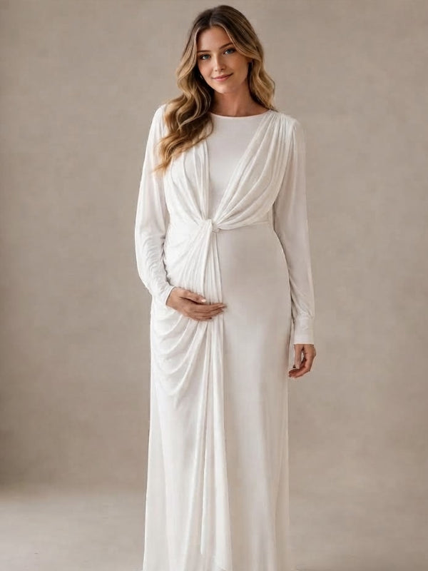 White jersey maternity maxi dress with draped cape overlay and long sleeves, designed for maternity photoshoot.