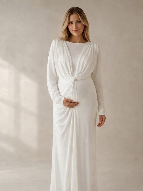 White jersey maternity maxi dress with draped cape overlay and long sleeves, designed for maternity photoshoot.