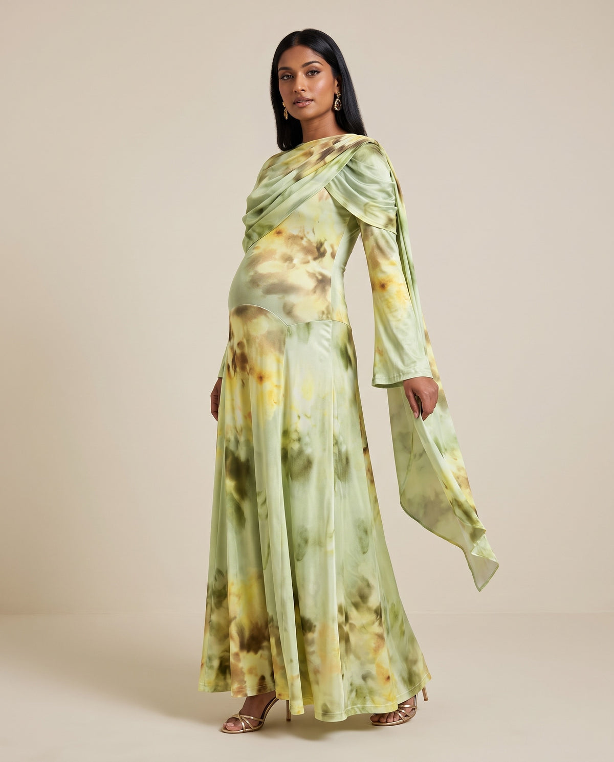 Green printed satin maternity maxi dress with draped cape shoulder and bell sleeves, designed for baby showers.