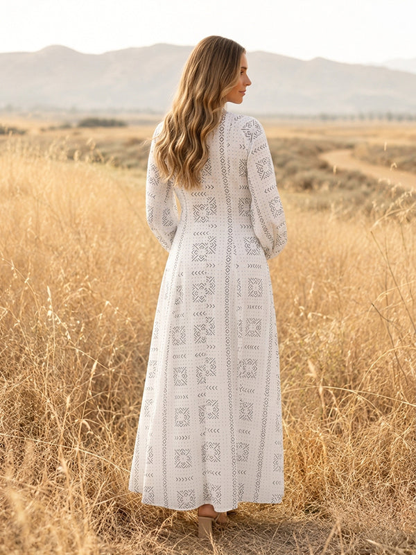 Back view of white eyelet embroidered maternity maxi dress with band collar, button front and long sleeves, designed for maternity photoshoot.