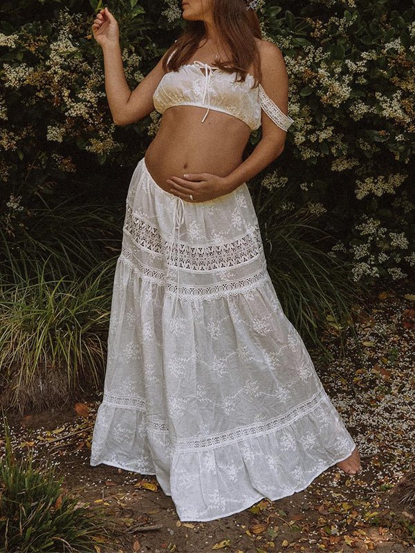White eyelet embroidered maternity two-piece set with tie-front crop top and tiered lace-trim maxi skirt, designed for maternity photoshoot.