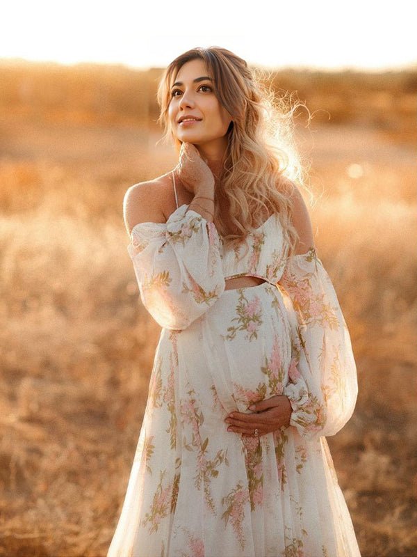 White floral chiffon maternity maxi dress with off-shoulder cami straps, lantern sleeves, cut-out waist and open back, designed for maternity photoshoot.