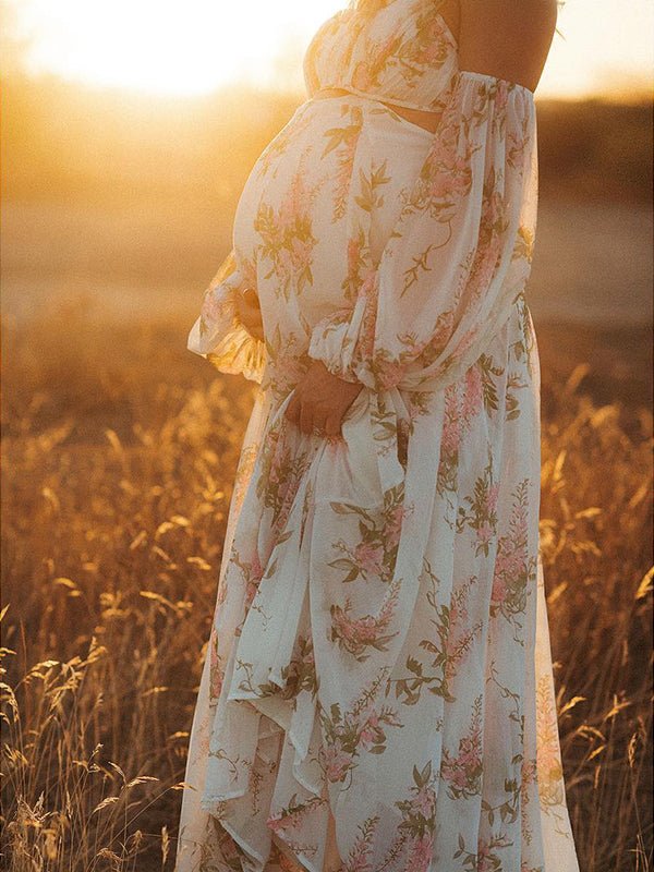 Side view of white floral chiffon maternity maxi dress with off-shoulder cami straps, lantern sleeves, cut-out waist and open back, designed for maternity photoshoot.