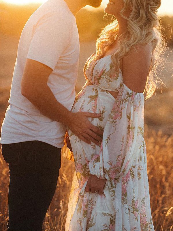 Side view of white floral chiffon maternity maxi dress with off-shoulder cami straps, lantern sleeves, cut-out waist and open back, designed for maternity photoshoot.