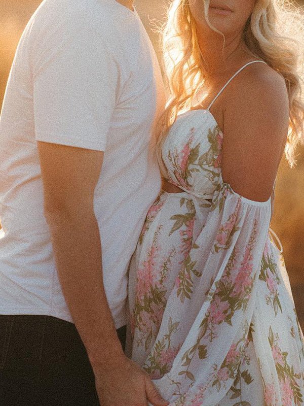 Side view of white floral chiffon maternity maxi dress with off-shoulder cami straps, lantern sleeves, cut-out waist and open back, designed for maternity photoshoot.