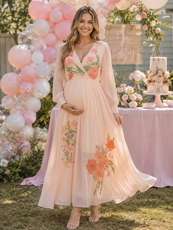 Blush pink chiffon maternity maxi dress with V-neck, sheer long sleeves and floral embroidery, designed for baby shower.