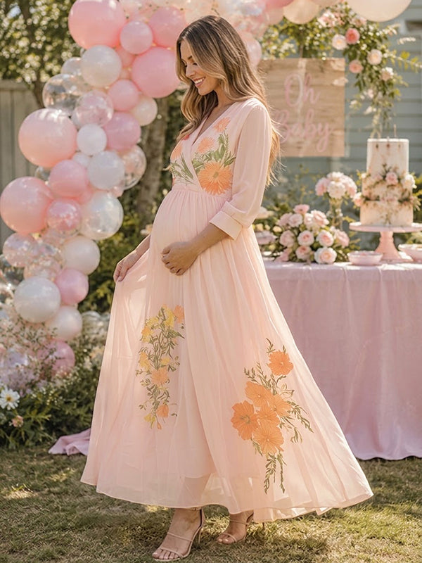 Side view of blush pink chiffon maternity maxi dress with V-neck, sheer long sleeves and floral embroidery, designed for baby shower.