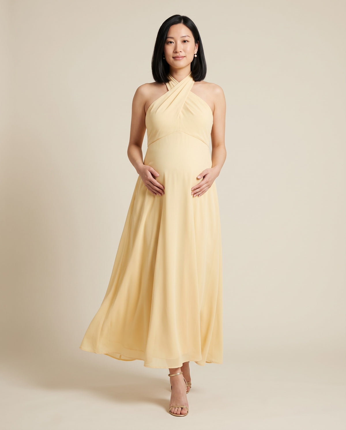 Yellow flowing maternity maxi dress with crossed halter neckline, designed for baby showers.
