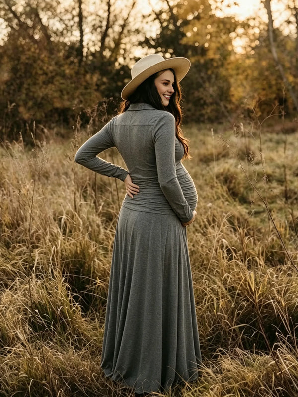 Back view of grey jersey maternity maxi dress with collar, button placket, ruched waist and flowy skirt, designed for maternity photoshoot.