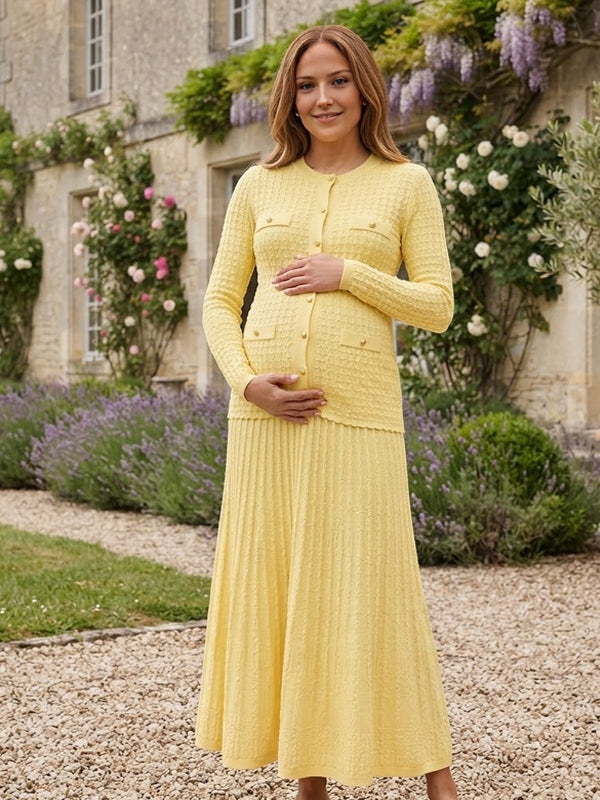 Yellow knit maternity two-piece set with button cardigan and pleated maxi skirt, designed for maternity photoshoot.