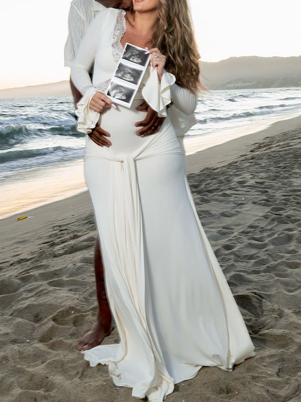 Ivory maternity maxi dress with lace-trimmed V-neck, ruffle bell cuffs, draped sash and mermaid train, designed for maternity photoshoot.