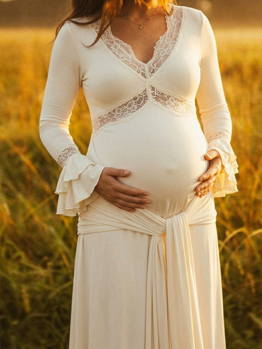 Ivory maternity maxi dress with lace-trimmed V-neck, ruffle bell cuffs, draped sash and mermaid train, designed for maternity photoshoot.