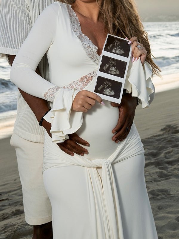 Ivory maternity maxi dress with lace-trimmed V-neck, ruffle bell cuffs, draped sash and mermaid train, designed for maternity photoshoot.