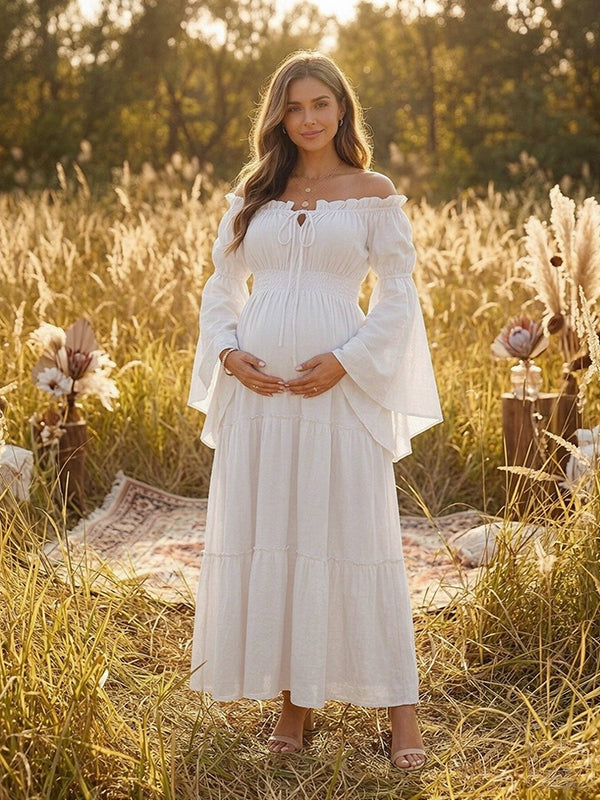 White boho maternity maxi dress with off-shoulder smocked bodice, bell sleeves and tiered skirt, designed for maternity photoshoot.