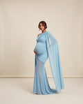 Blue mesh maternity maxi dress with one-shoulder neckline and flowing cape panel, designed for maternity photoshoots and formal events.