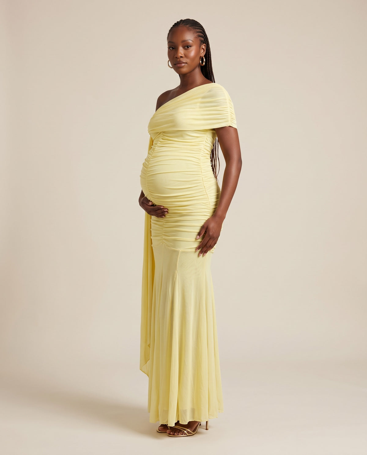Yellow mesh maternity maxi dress with one-shoulder draped panel and ruched bodice, designed for maternity photoshoots.