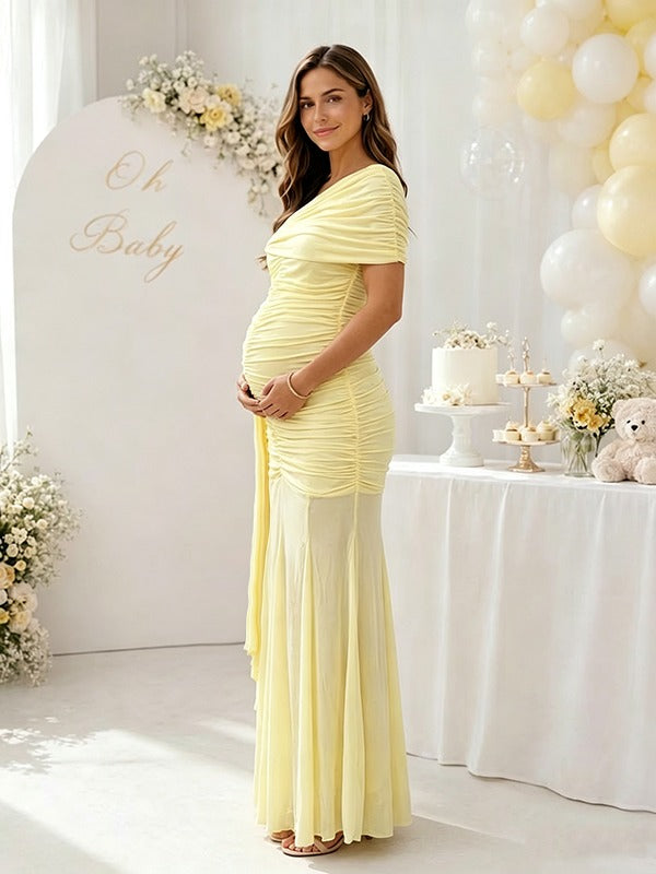 Side view of yellow ruched mesh maternity maxi dress with one-shoulder drape and sheer skirt, designed for baby shower.