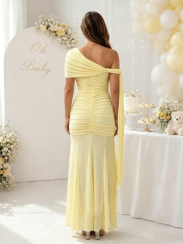 Back view of yellow ruched mesh maternity maxi dress with one-shoulder drape and sheer skirt, designed for baby shower.