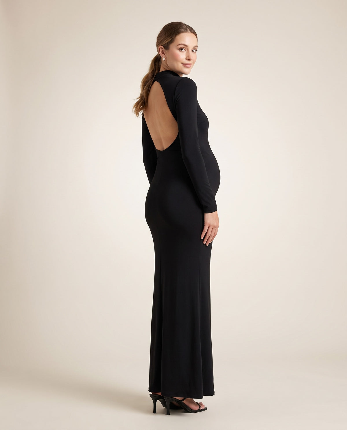 Black jersey maternity maxi dress with mock neck and open back, designed for evening and photoshoot wear.