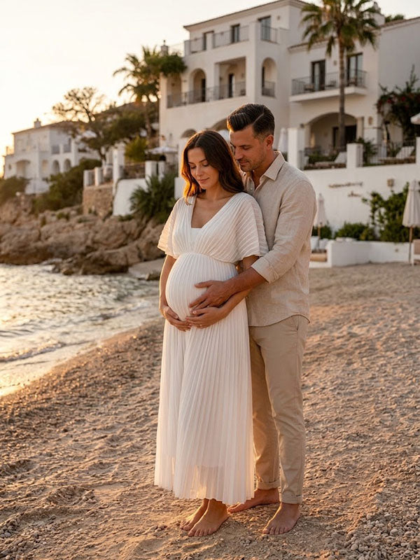 White pleated chiffon maternity maxi dress with V-neck and flutter sleeves, designed for maternity photoshoot.