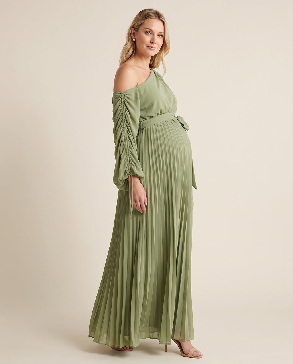 Green pleated one-shoulder maternity maxi dress with ruched sleeve and tie waist, shown on a pregnant model in studio.