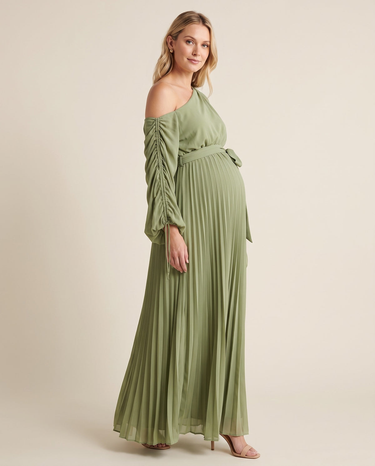 Green pleated one-shoulder maternity maxi dress with ruched sleeve and tie waist, shown on a pregnant model in studio.