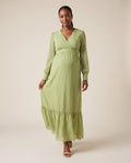 Green polka dot chiffon maternity maxi dress with wrap neckline and ruffle hem, shown on a pregnant model in studio.