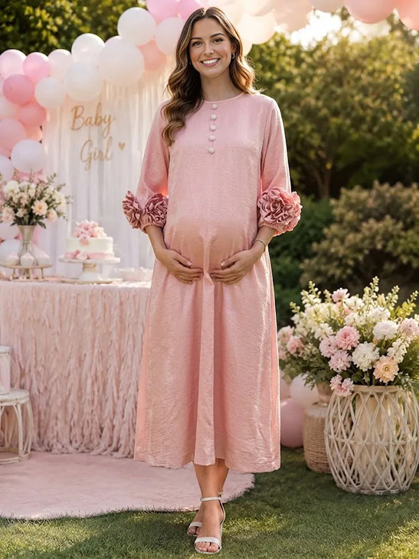 Pink textured maternity midi dress with button placket and 3D rosette sleeve cuffs, designed for baby shower.