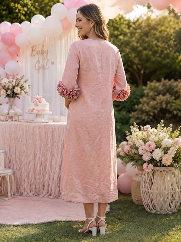 Back view of pink textured maternity midi dress with button placket and 3D rosette sleeve cuffs, designed for baby shower.