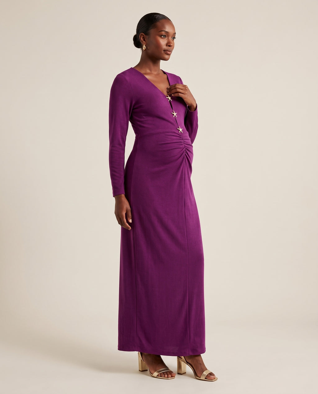 Purple ruched maternity maxi dress with gold star buttons and long sleeves, designed for wedding guest wear.