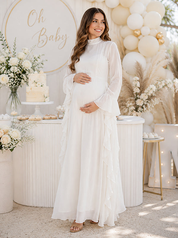 White chiffon maternity maxi dress with mock neck, bell sleeves and side ruffles, designed for baby shower.