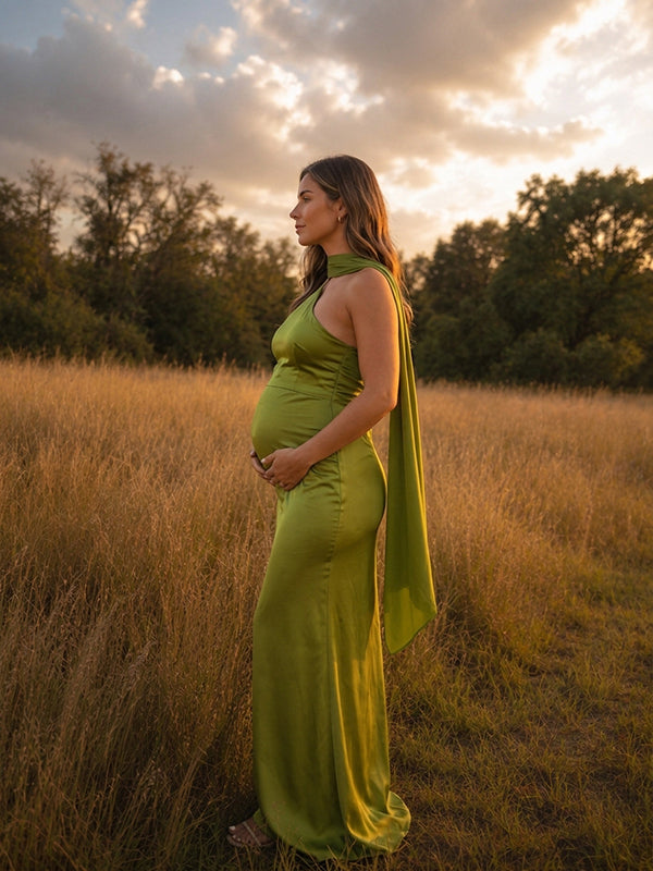 Side view of chartreuse green satin maternity maxi dress with halter neck and long trailing scarf, designed for maternity photoshoot.