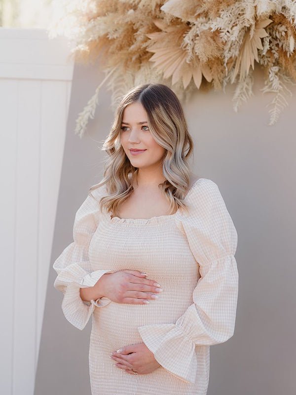 Ivory smocked maternity midi dress with off-shoulder neckline and puff sleeves, designed for baby shower.