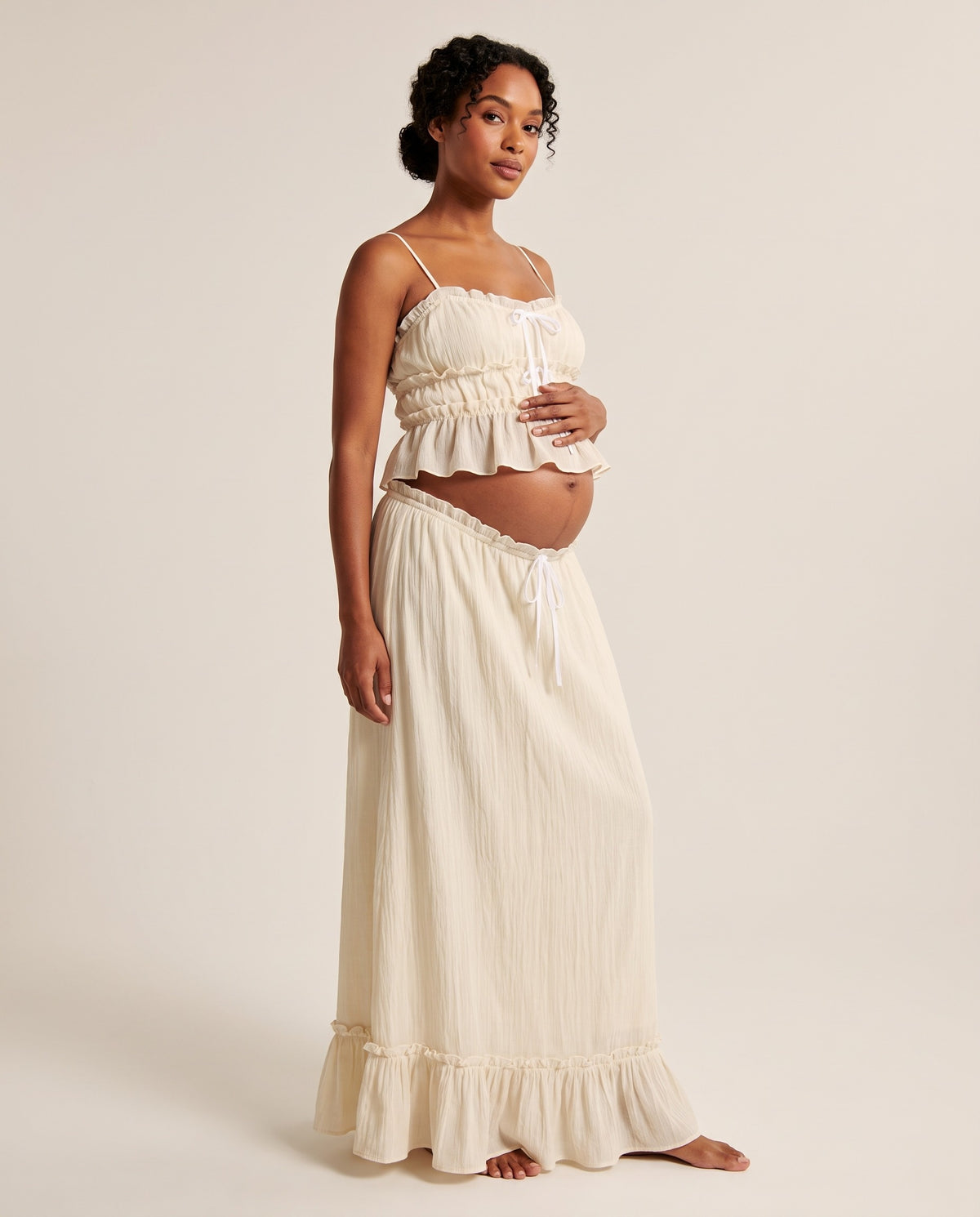 Ivory crinkled cotton maternity two-piece set with ruffle cami top and tie-front maxi skirt, designed for baby shower and maternity photoshoots.