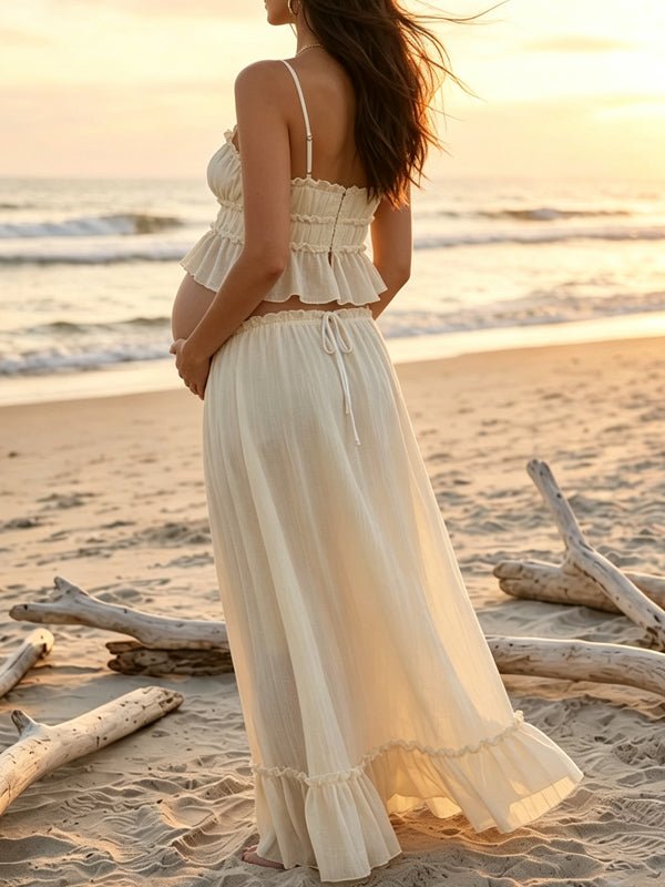 Back view of ivory maternity two-piece set with smocked ruffle cami crop top and drawstring ruffle-hem maxi skirt, designed for maternity photoshoot.
