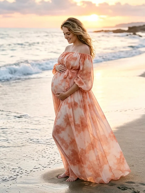Coral pink tie-dye chiffon maternity maxi dress with off-shoulder neckline, balloon sleeves and tie waist, designed for photoshoot and baby shower.