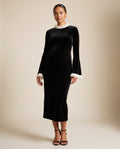Black velvet maternity midi dress with ivory ruffle collar and cuffs, shown on a pregnant model in studio.