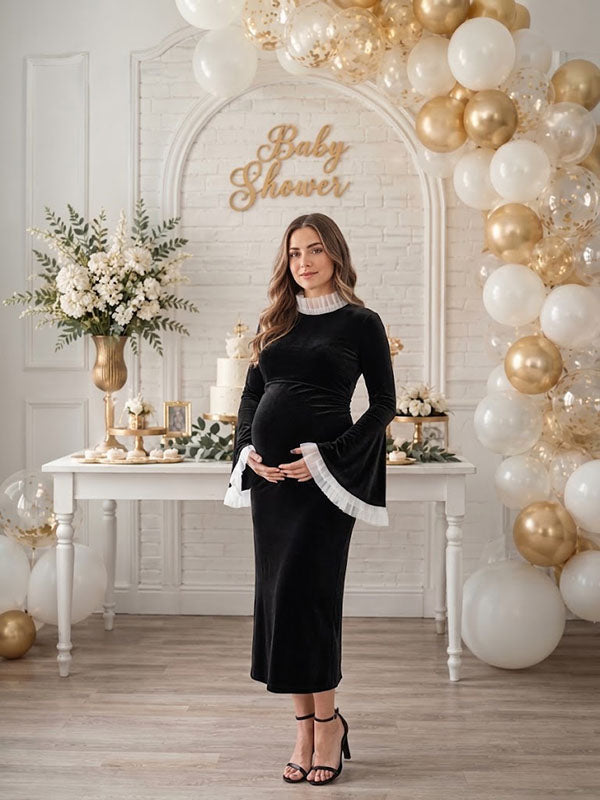 Black velvet maternity midi dress with ruffled mock neck and bell sleeves, designed for baby shower.