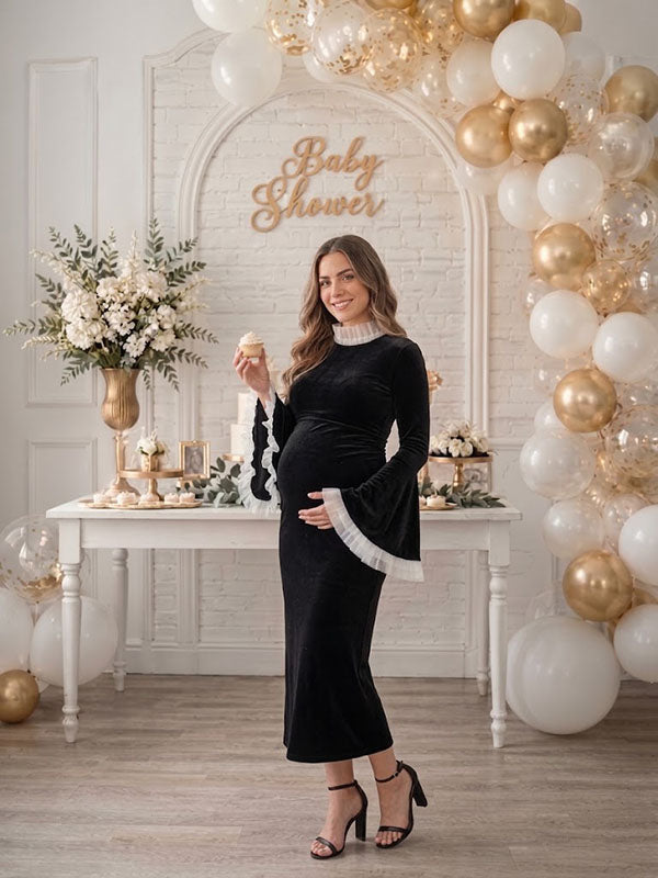 Black velvet maternity midi dress with ruffled mock neck and bell sleeves, designed for baby shower.
